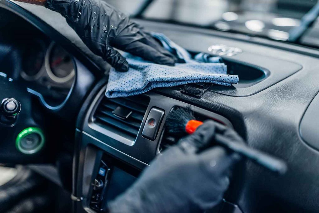 [Imagem de um profissional realizando polimento técnico na lateral de um carro preto]
